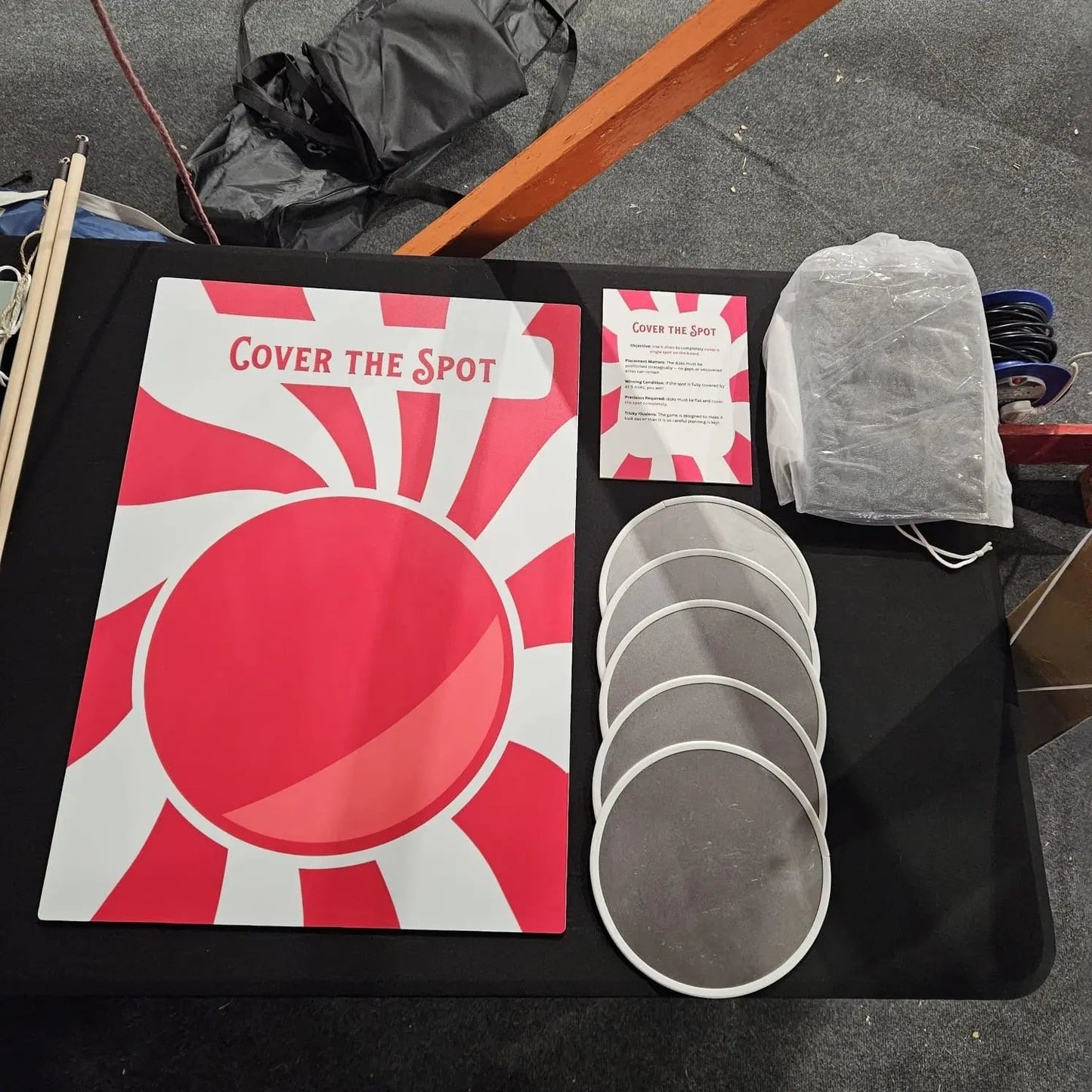 Game components including a red and white board titled 'Cover the Spot' on a black surface.