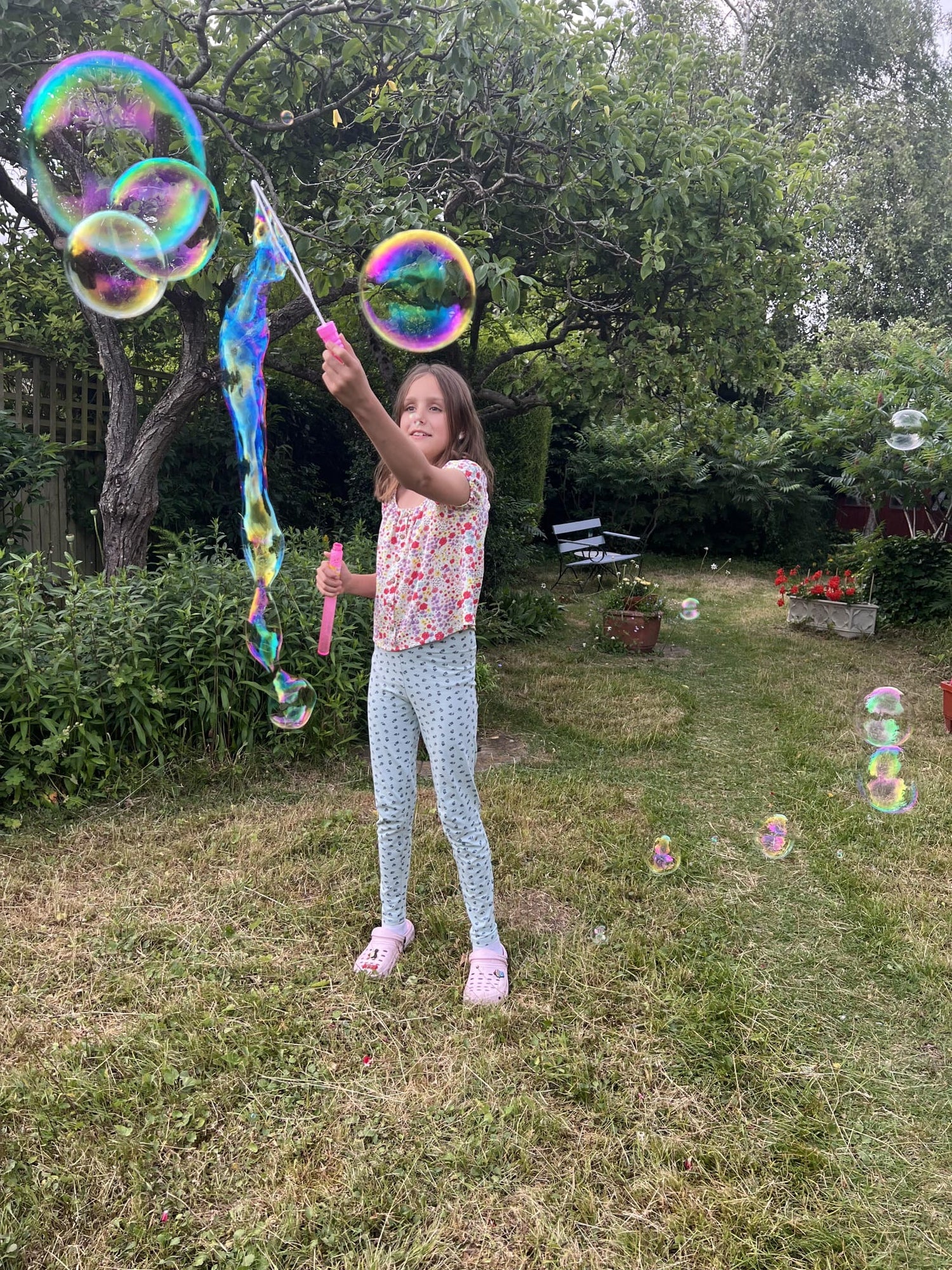 Young girl playing with bubble wands and bubbles in a garden