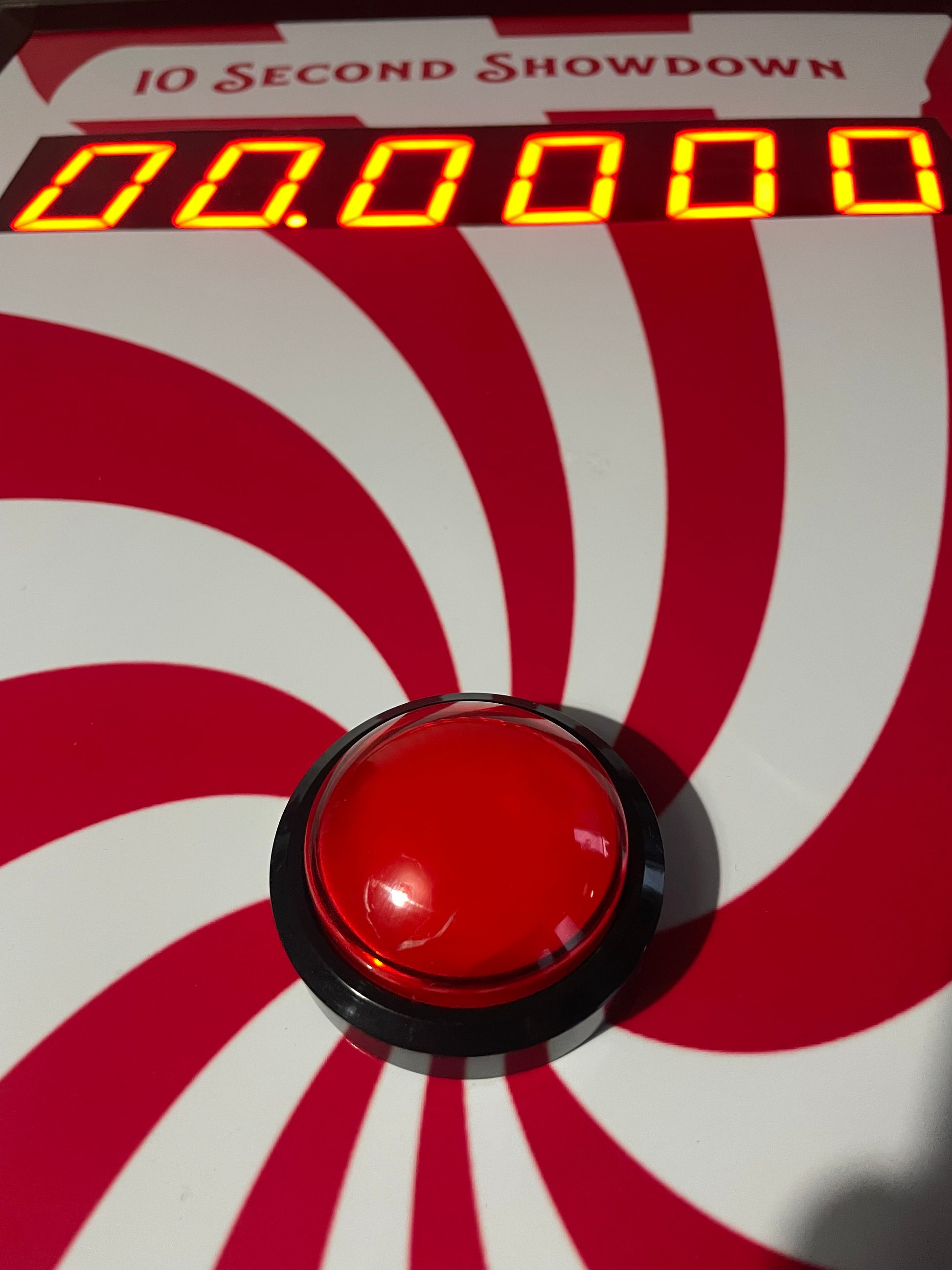 10 Second challenge - Red button on a device with a digital display against a red and white striped background