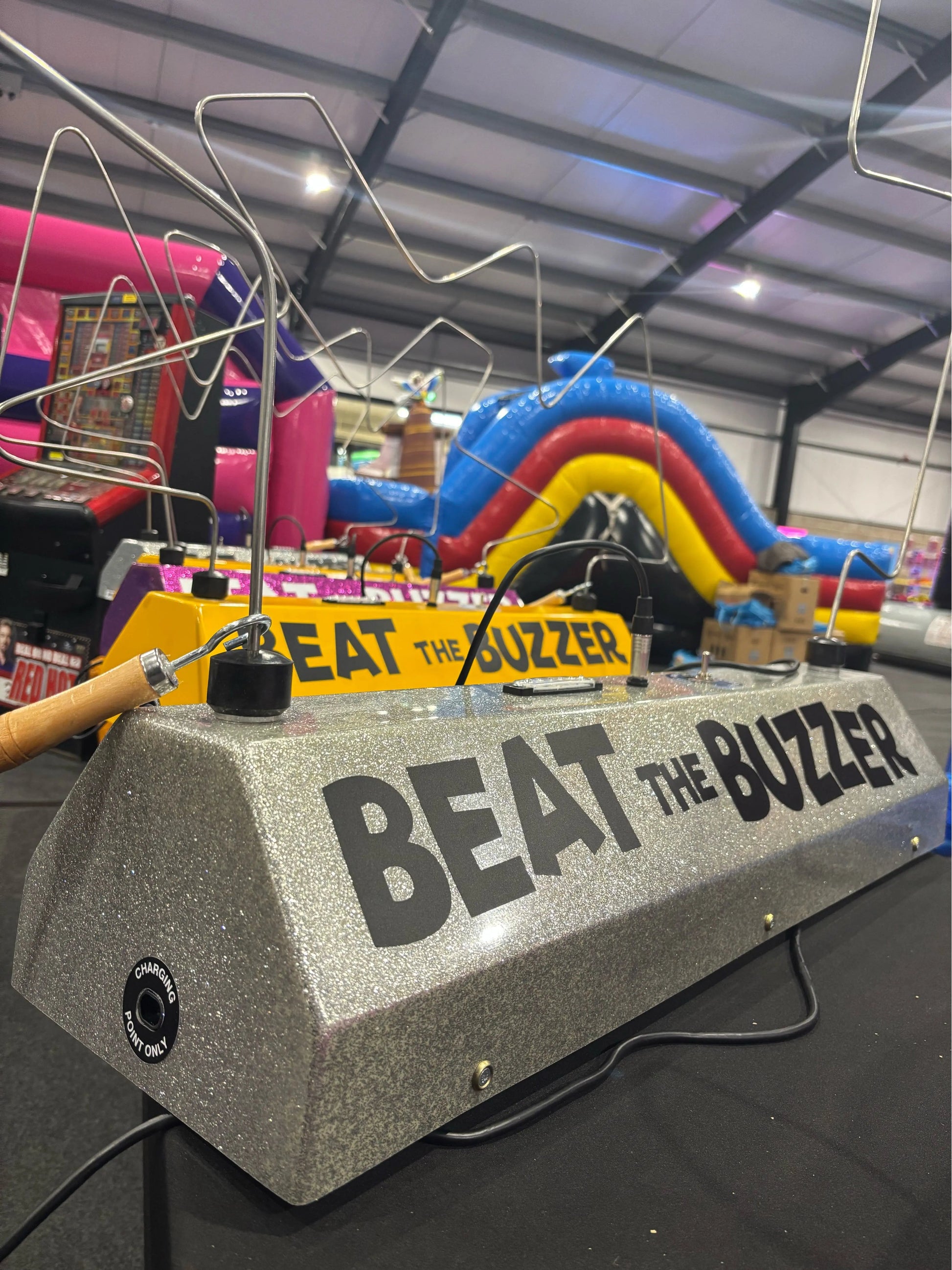 Game console with 'Beat the Buzzer' text in an indoor setting with bouncy Castles