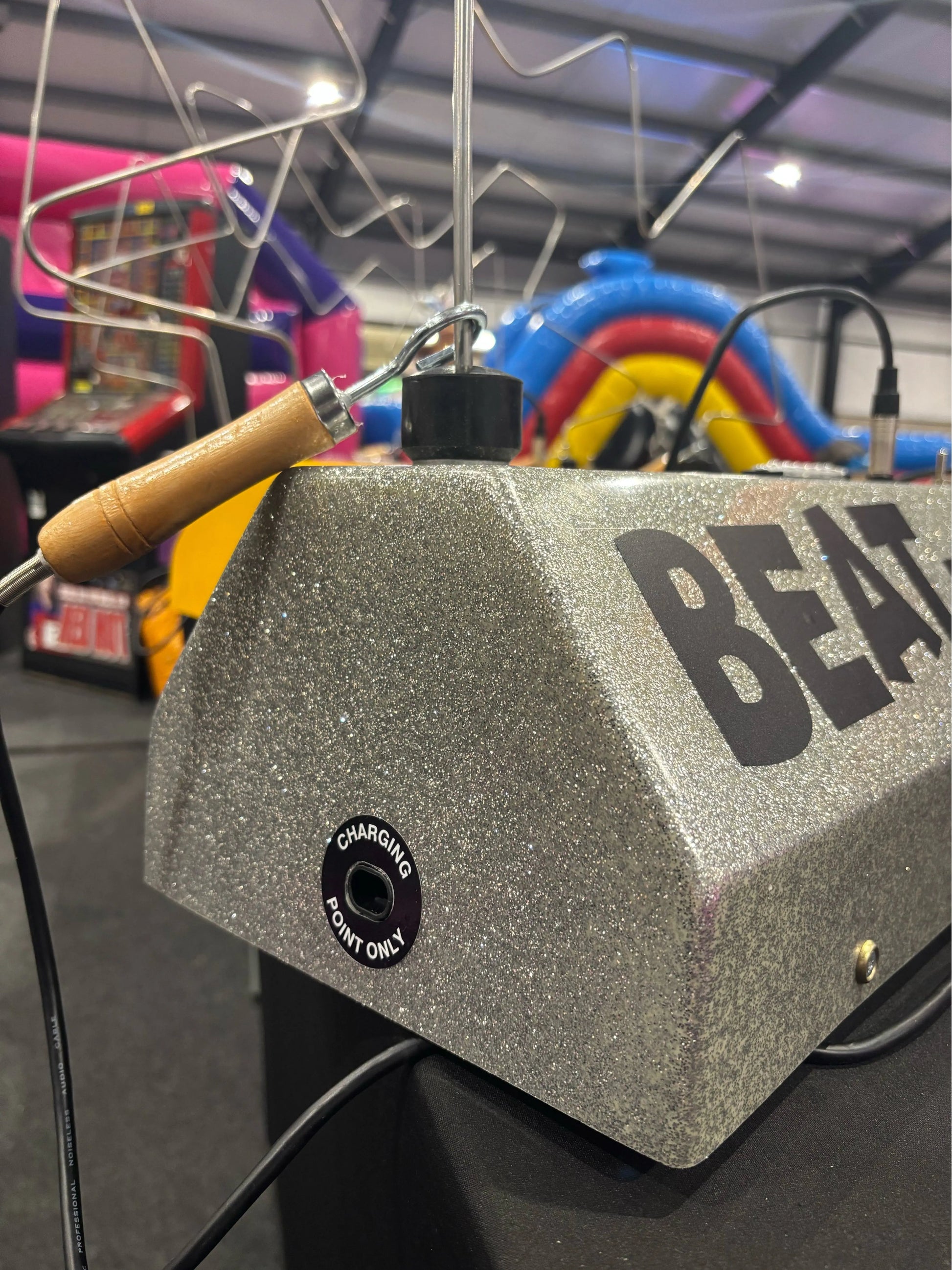 Gray electronic device with 'BEAT' branding in a colorful indoor setting