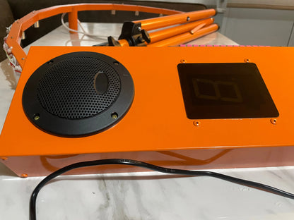 Orange industrial machine with a speaker and digital display on a white surface