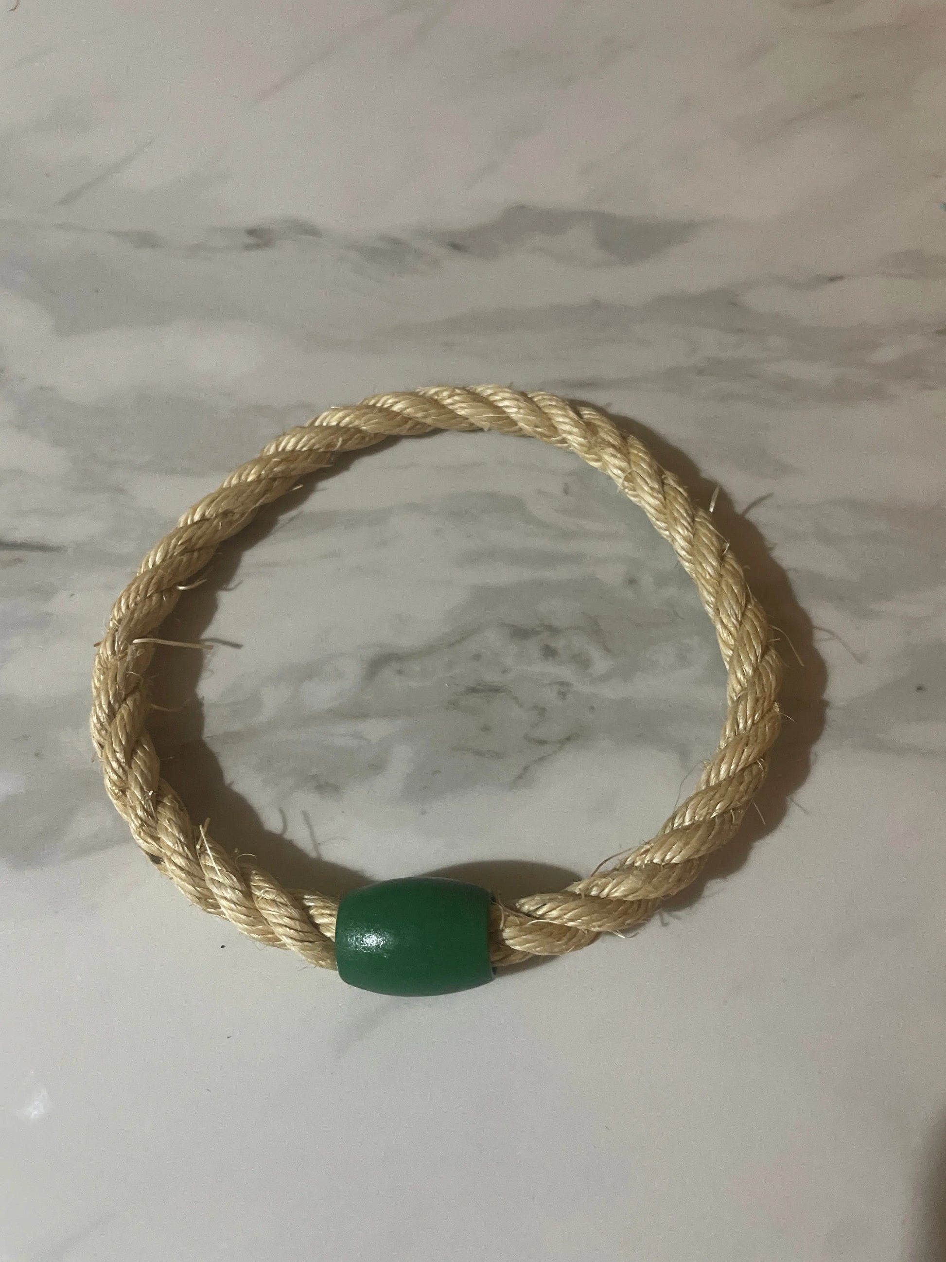Rope toy with a green bead on a marble surface