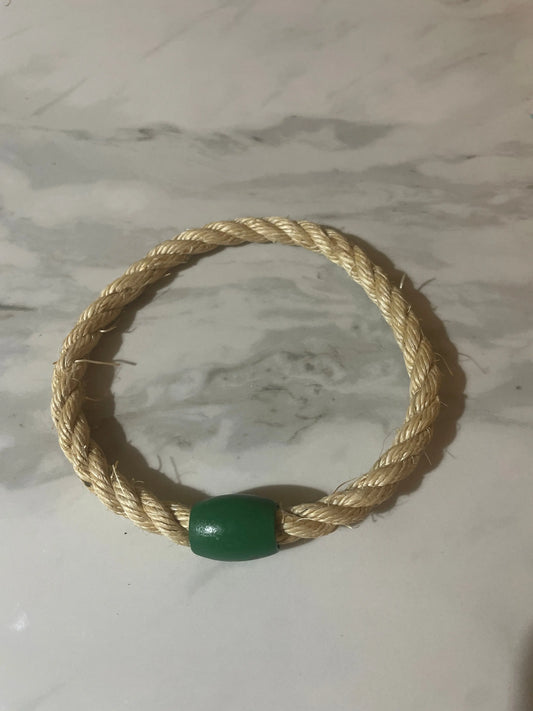 Rope toy with a green bead on a marble surface