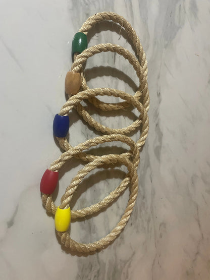 Set of five braided rope bracelets with colorful beads on a marble surface