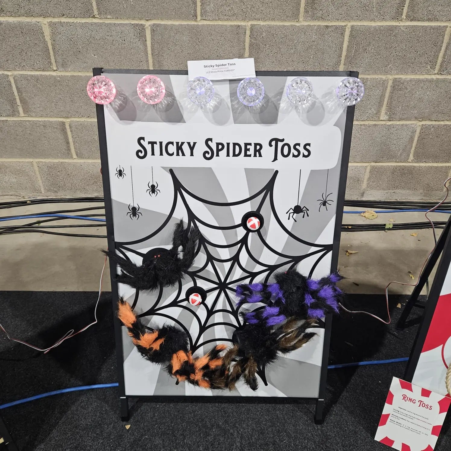 Halloween game setup with 'Sticky Spider Toss' on a brick wall background