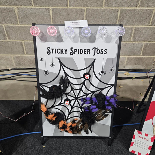 Halloween game setup with 'Sticky Spider Toss' on a brick wall background